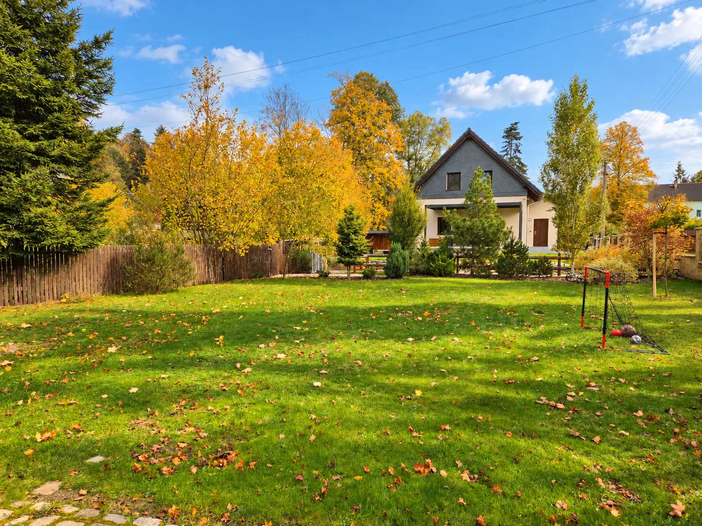 Der eingezäunte Garten des Hauses mit Rasen und Fußballtor im Herbst